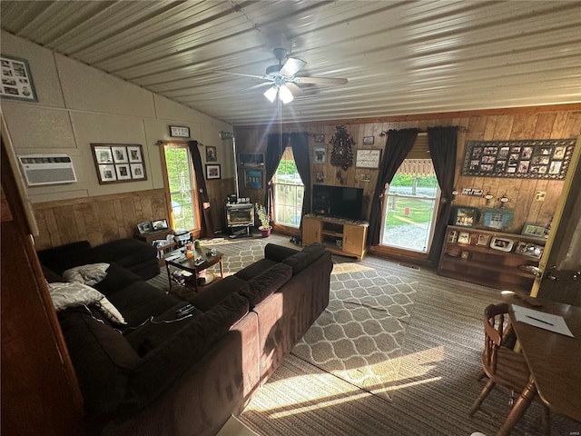 living room featuring ceiling fan, a wall mounted AC, a wood stove, wooden walls, and lofted ceiling