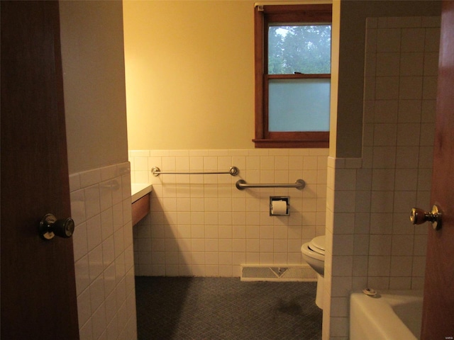 bathroom with toilet, tile floors, and tile walls