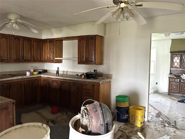 kitchen with a textured ceiling, dark brown cabinets, and ceiling fan