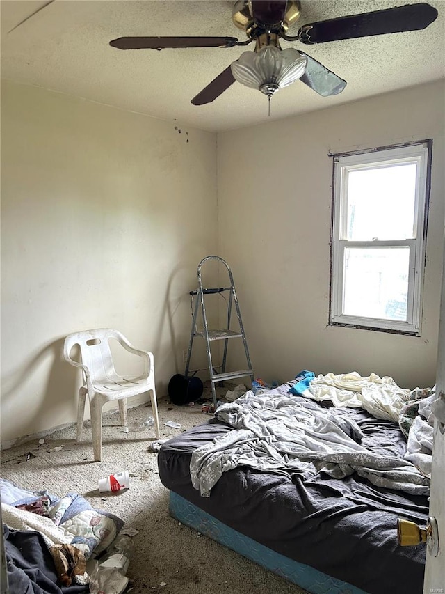 carpeted bedroom with ceiling fan and a textured ceiling