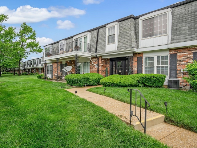 view of front of property with a balcony, central air condition unit, and a front yard