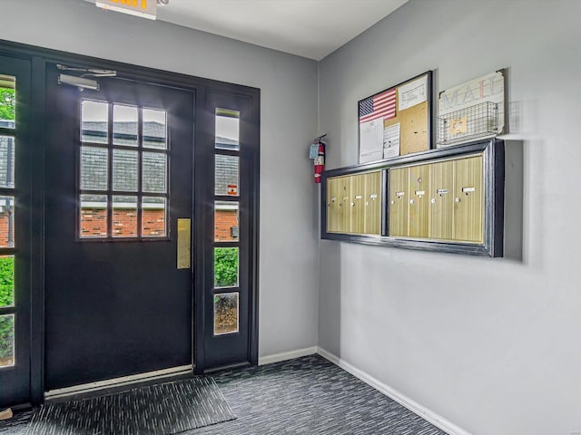 doorway featuring dark carpet and a mail area