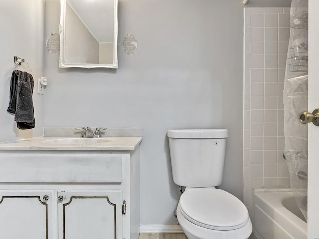 full bathroom featuring vanity, tiled shower / bath, and toilet