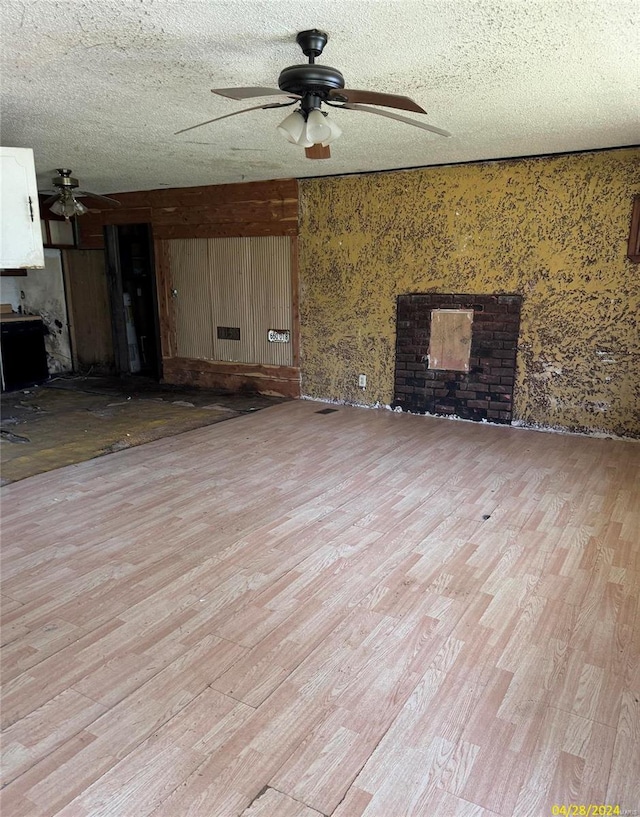 unfurnished living room with a textured ceiling, ceiling fan, and light wood-type flooring