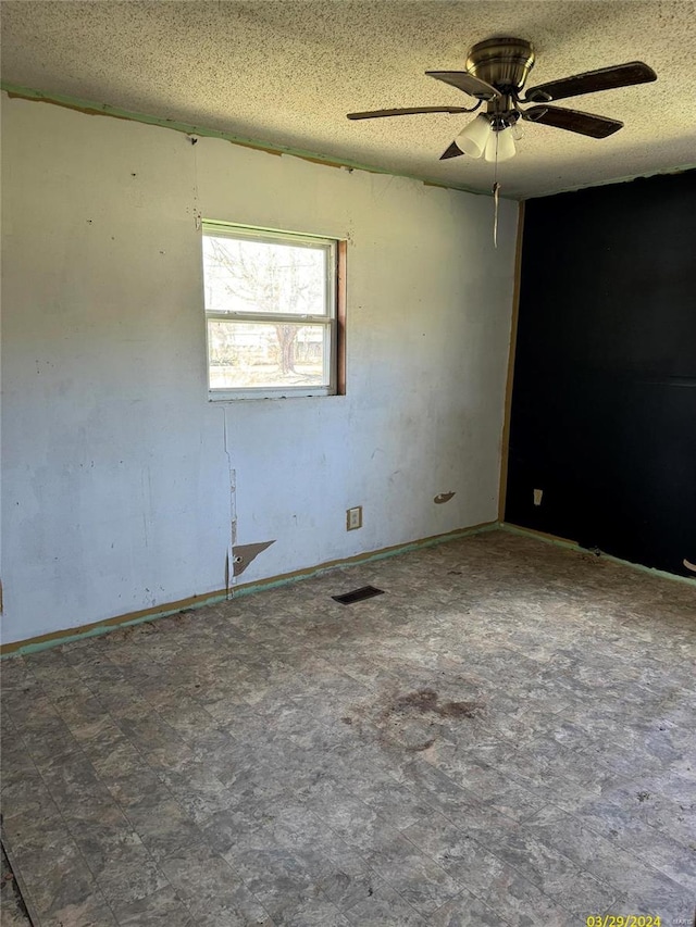 spare room with dark tile flooring, ceiling fan, and a textured ceiling