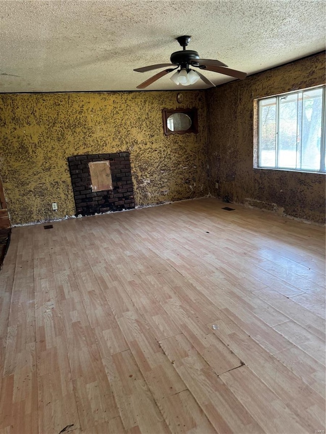 empty room with hardwood / wood-style floors, ceiling fan, and a textured ceiling