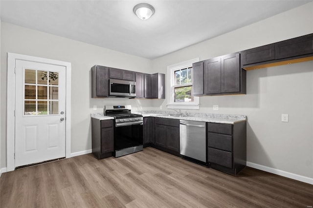 kitchen with hardwood / wood-style floors, sink, stainless steel appliances, and light stone countertops