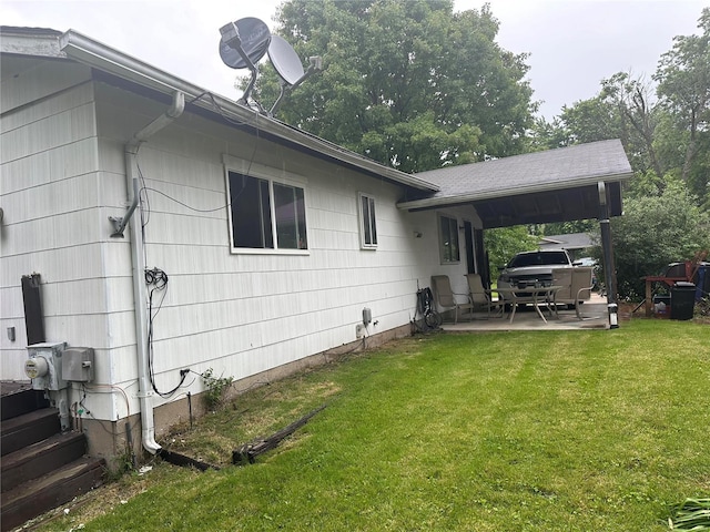 view of side of property with a patio and a lawn