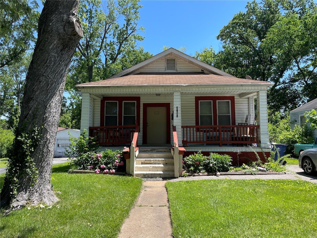 bungalow-style house with a garage, a front yard, and a porch