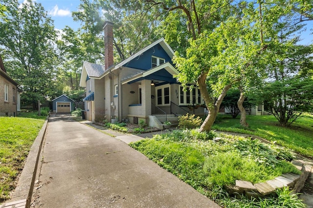 bungalow-style house with a front lawn, a garage, an outdoor structure, and covered porch