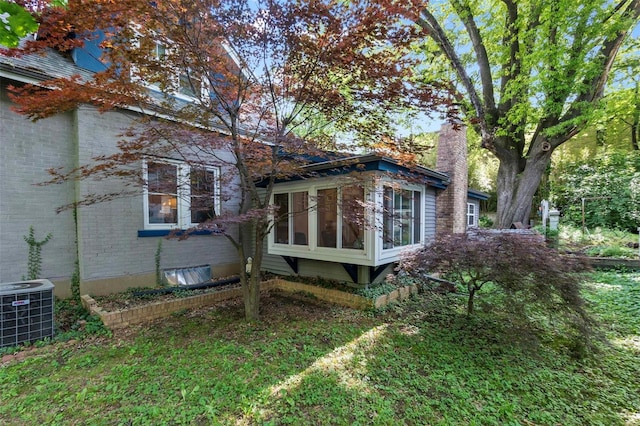 back of house featuring a sunroom, central AC, and a lawn