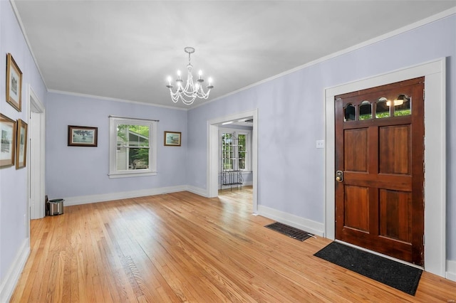 entrance foyer with a wealth of natural light, a notable chandelier, ornamental molding, and light wood-type flooring