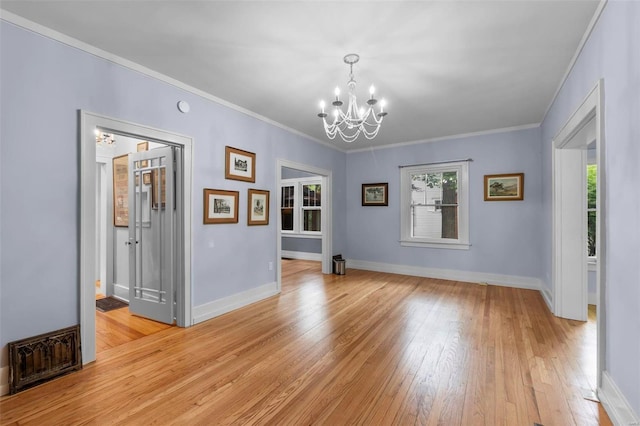 unfurnished room featuring ornamental molding, light hardwood / wood-style floors, and a chandelier