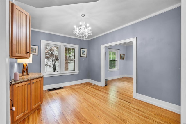 unfurnished dining area featuring a chandelier, light wood-type flooring, and ornamental molding