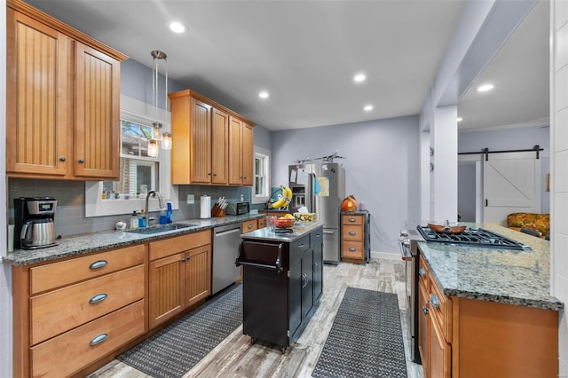 kitchen with tasteful backsplash, a center island, a barn door, sink, and appliances with stainless steel finishes