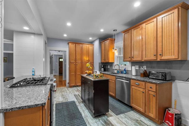 kitchen with light hardwood / wood-style floors, a kitchen island, stainless steel dishwasher, gas range, and sink