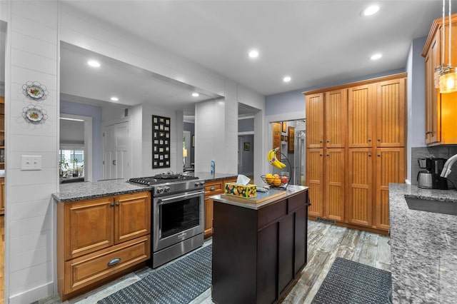 kitchen with light stone countertops, hardwood / wood-style flooring, a kitchen island, sink, and gas range