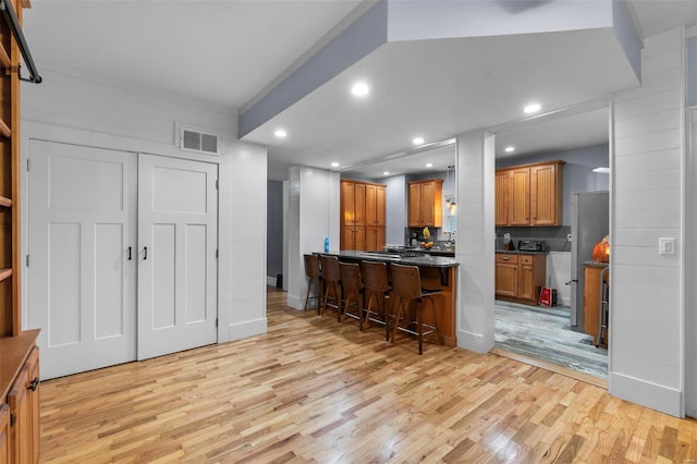 kitchen featuring kitchen peninsula, tasteful backsplash, light wood-type flooring, and a breakfast bar