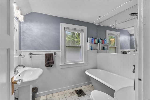 bathroom with vaulted ceiling, toilet, tile floors, a tub, and sink