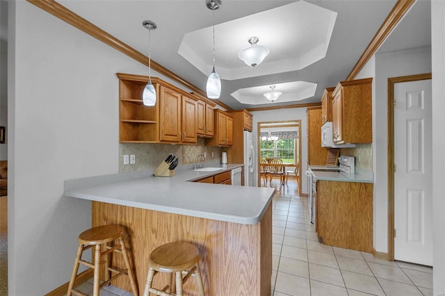 kitchen featuring white appliances, a raised ceiling, decorative backsplash, a kitchen bar, and kitchen peninsula