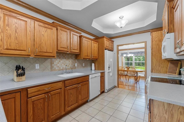 kitchen featuring light tile patterned floors, white appliances, a tray ceiling, and sink