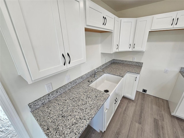 kitchen featuring light wood-type flooring, white cabinets, light stone counters, and sink