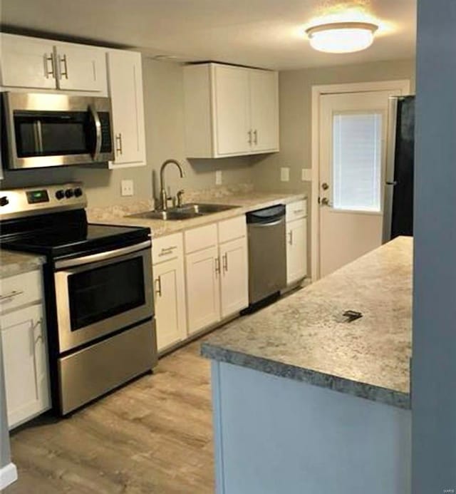 kitchen with sink, light hardwood / wood-style floors, white cabinetry, and stainless steel appliances