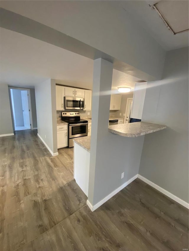 kitchen with wood-type flooring, white cabinets, kitchen peninsula, and appliances with stainless steel finishes