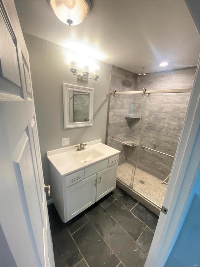 bathroom with a shower with door, tile patterned floors, and vanity