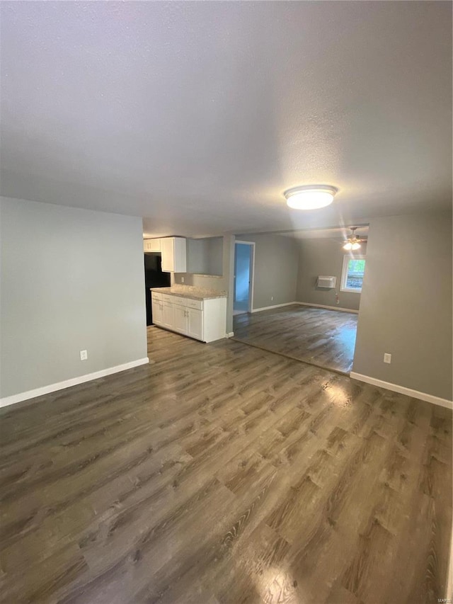 unfurnished living room with a textured ceiling and dark hardwood / wood-style flooring