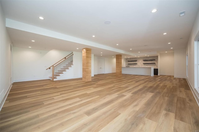 unfurnished living room featuring light wood-type flooring and brick wall