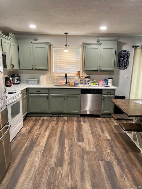 kitchen featuring decorative light fixtures, stainless steel appliances, green cabinetry, and sink