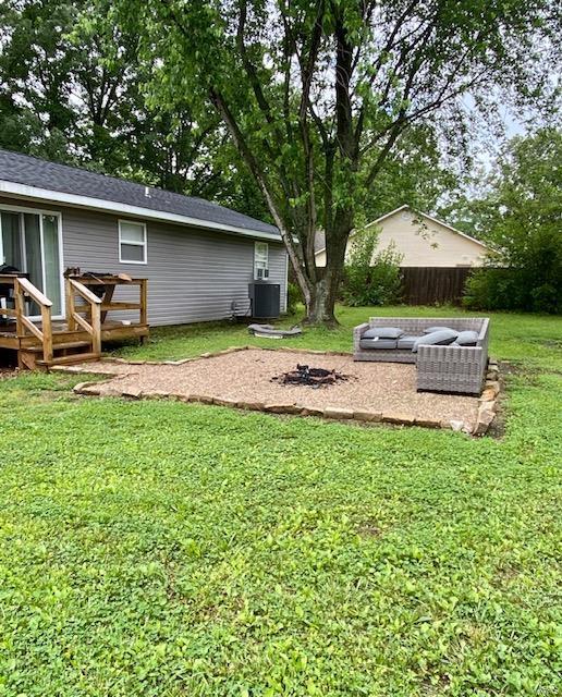 view of yard featuring an outdoor fire pit, cooling unit, a wooden deck, and fence