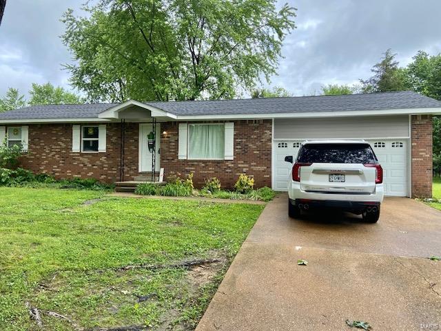 ranch-style home with an attached garage, brick siding, driveway, and a front yard