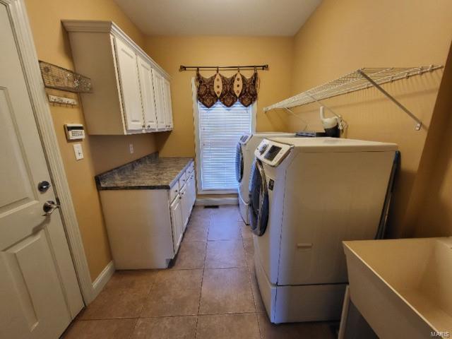 clothes washing area with tile flooring, washer and clothes dryer, sink, and cabinets