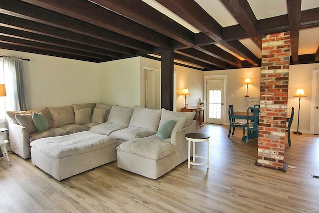 living room featuring beam ceiling, hardwood / wood-style flooring, and brick wall