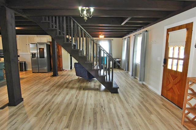 basement with an inviting chandelier, stainless steel fridge with ice dispenser, and light wood-type flooring