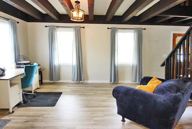 living room with beam ceiling, a healthy amount of sunlight, and light hardwood / wood-style flooring