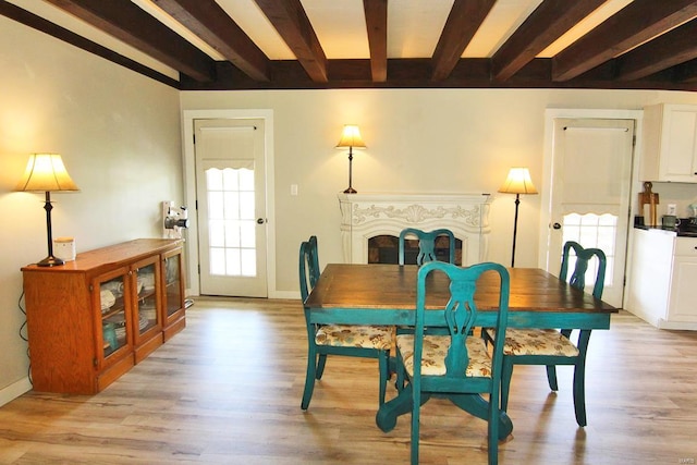 dining area with beam ceiling and light wood-type flooring