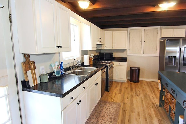 kitchen with light hardwood / wood-style flooring, stainless steel appliances, white cabinets, beam ceiling, and sink