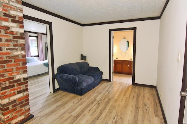 sitting room featuring brick wall, light hardwood / wood-style floors, and crown molding