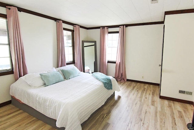 bedroom with hardwood / wood-style flooring, ornamental molding, and multiple windows