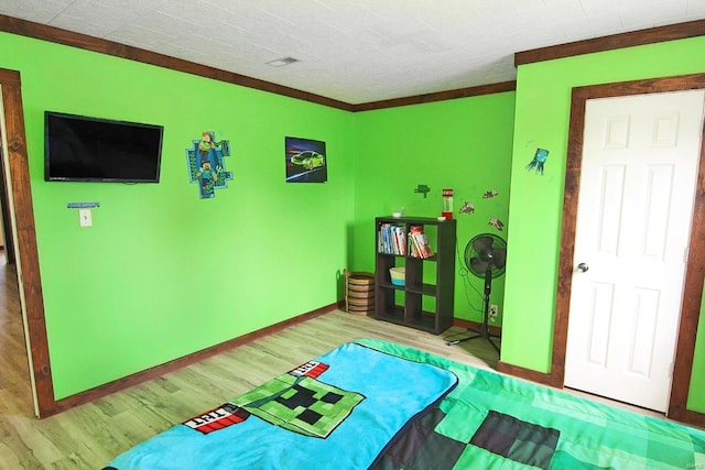 rec room with ornamental molding and wood-type flooring