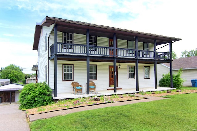 view of property with a front lawn, a balcony, and covered porch