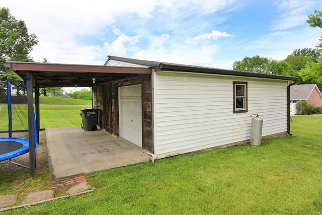 view of shed / structure featuring a garage, a trampoline, and a yard