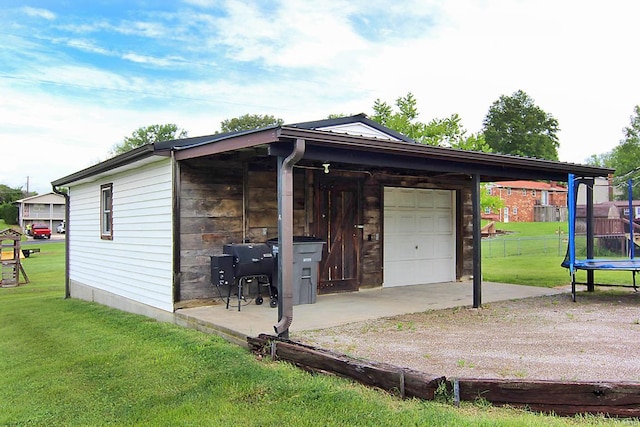 garage featuring a lawn and a trampoline