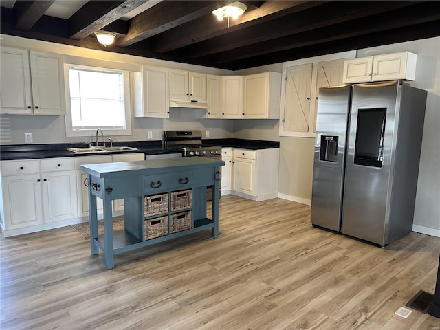 kitchen with beamed ceiling, a sink, appliances with stainless steel finishes, white cabinets, and light wood finished floors