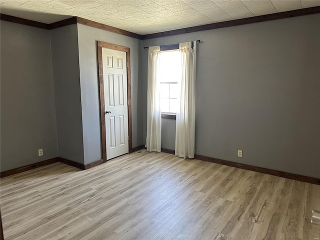 unfurnished room with baseboards, light wood-style floors, and crown molding