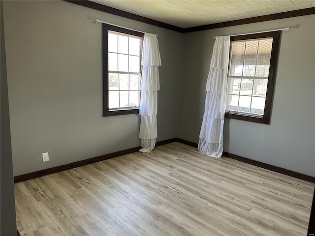 empty room featuring light wood-style flooring, baseboards, and ornamental molding