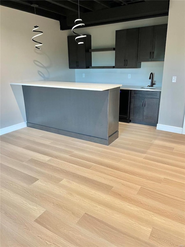 kitchen with light hardwood / wood-style flooring, decorative light fixtures, and sink